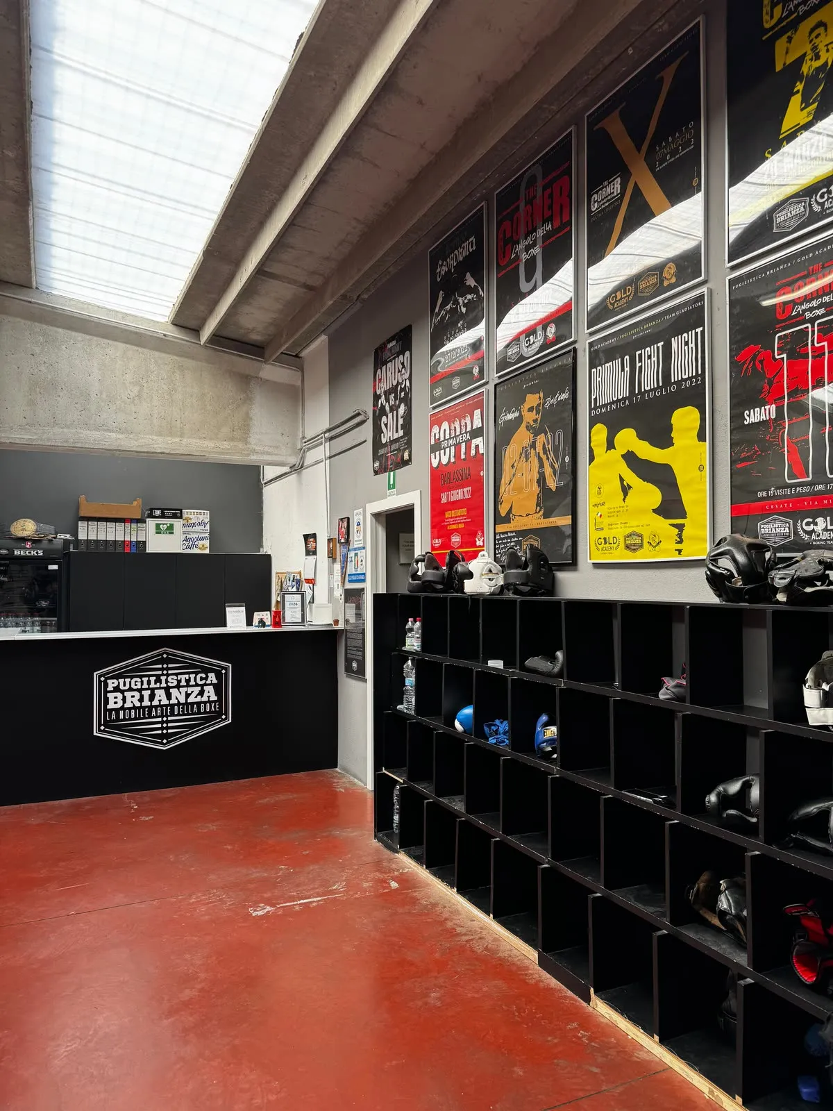 Ingresso e reception della Pugilistica Brianza: bancone con logo, locandine eventi e scaffali attrezzatura